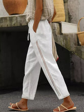 White linen wide leg cropped pants featuring delicate lace trim along side seams and hem for a stylish look
