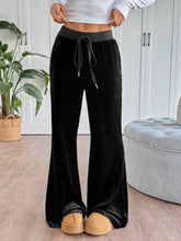 Black velvet wide-leg drawstring pants with flare silhouette and adjustable waistband for comfortable wear care instructions included