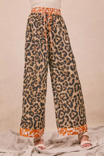 Wide-leg bibi leopard print trousers in orange and beige tones with drawstring waistband and floral cuffs