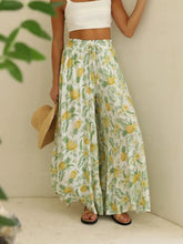 White wide leg pants with vibrant yellow and green tropical pineapple leaf print and drawstring paperbag waist