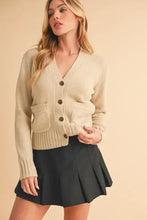 Cream-colored knit cardigan with ribbed hem button closure and pockets