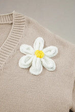 White daisy brooch with yellow center on beige floral cardigan sweater