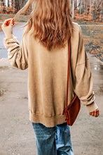 Woman in beige game day graphic sweatshirt, long sleeve length, jeans, and reddish-brown crossbody bag