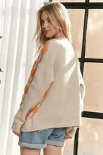 Cream oversized heart sweater cardigan with orange pom-poms and Adora button