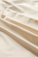 Cream-colored satin bedsheet with subtle folds in pleated tennis skirt collection