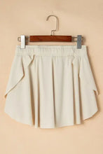 Cream pleated tennis skirt with elastic waistband, side pockets, high-waisted shorts
