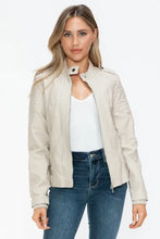 Woman in beige leather biker jacket with zip pockets and blue jeans