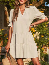 Beige tiered dress with ruffled sleeves, V-neckline, and smocked details