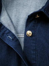 Gold-toned button with textured edge on dark denim fabric of belted button-down midi denim dress