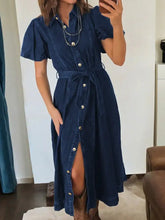 A navy blue denim dress with short puffed sleeves, button-front design, and tied waist belt midi denim dress