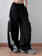 Black cargo pants with white three stripe side panels and drawstring waistband in striped wide leg design