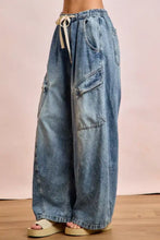 Light-wash denim baggy barrel jeans with cargo pockets and a drawstring waist for casual comfort and style