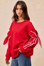 Red oversized fleece blend sweatshirt featuring white ribbon ties on bow detail sleeves with styling pairing tips