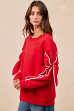 Red fleece blend oversized sweatshirt with white piping and tied bow sleeve details perfect for casual pairing tips