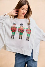 White oversized sweatshirt featuring sequin nutcrackers embroidery in red green and gold by bibi christmas