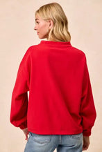 A vibrant red bibi christmas fleece buttoned oversized crewneck sweatshirt with long sleeves and pockets and care instructions