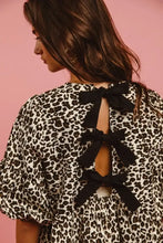 Back view of a biBi leopard denim dress featuring black and white print with three large black bow ties along the back