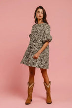 A woman wearing a black and white leopard denim dress with puffed sleeves and back contrast tie detail by bibi