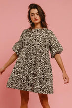 A woman wearing a black and white leopard denim dress with puffy sleeves and back contrast tie detail