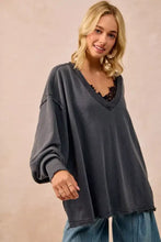Dark gray oversized sweatshirt in french terry with v-neck and frayed hem paired with white sneakers