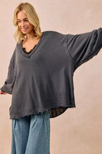 Dark gray oversized sweatshirt in french terry with v-neck and frayed hem paired with white sneakers