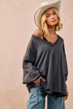 Dark gray oversized sweatshirt in french terry with v-neckline and frayed hem paired with white sneakers