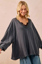 Dark gray oversized sweatshirt in french terry with v neck and frayed hem paired with white sneakers