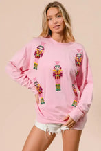 Pink BiBi sequin nutcrackers Christmas sweatshirt with colorful embroidered nutcracker designs on deep green accents