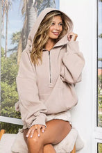 Beige fleece hoodie with elastic hem and soft oversized fit featuring ribbed cuffs and a chain necklace detail