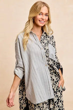 A stylish oversized button-up shirt featuring gray stripes jacquard and black floral jacquard mix with rolled cuffs
