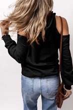 Woman in cold shoulder long sleeve hoodie with ruffles and blue jeans