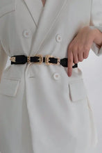 Black double buckle elastic belt with ornate gold detailing on white blazer dress