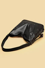 Black leather shoulder bag with studded details and adjustable strap