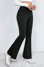 Black high-waisted flared pants styled with white sneakers and cropped top