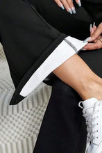 Black high-waisted flared pants with white sneakers, cropped top, and black and white athletic socks with silver zipper