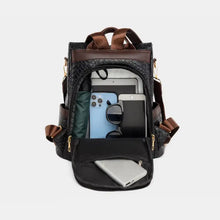 Black leather backpack bag with brown straps, open showing tablet and gadgets