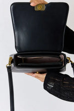 Black leather crossbody bag with gold hardware and adjustable strap