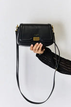 Black leather crossbody bag with gold hardware and adjustable strap