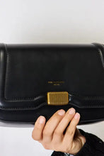 Black leather crossbody bag with gold hardware and flap closure