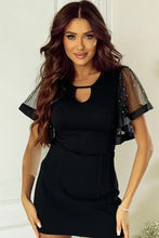 Woman in black mini dress with sheer embellished short sleeve and keyhole neck