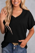 Woman in black textured V-neck short sleeve top and blue denim jeans