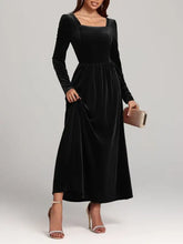 Woman in velvet square neck long sleeve dress with gold heels and clutch