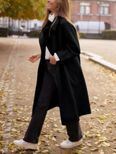 Oversized black wool coat with white collar, cuffs, and gold buttons