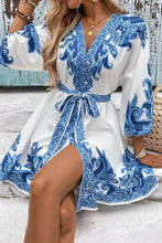 Blue and white paisley print dress with V-neck, long sleeves, tie waist, and side slit