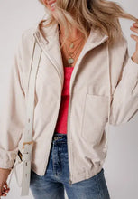 Beige zip-up bomber jacket with black piping, hood, and pockets