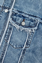 Blue distressed denim jacket with raw hem, frayed edges, and pearl buttons
