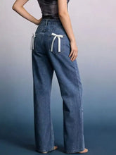 Back view of blue denim wide leg jeans featuring white ribbon bows on the back pockets for a stylish look