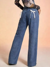 Back view of blue denim wide leg jeans with white ribbon ties at the back pockets bow back wide leg jeans