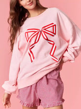 Pink oversized bow crew neck sweatshirt with bold red and white ribbon graphic machine wash cold recommended