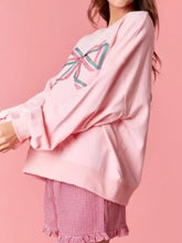 Pink oversized bow crew neck sweatshirt showing back with colorful embroidered bow machine wash cold recommended